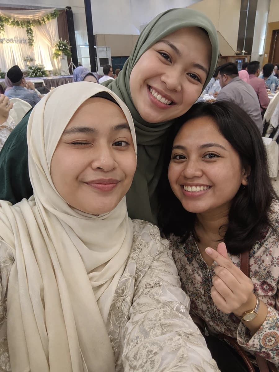 Three cousins huddled together for a playful wedding selfie
