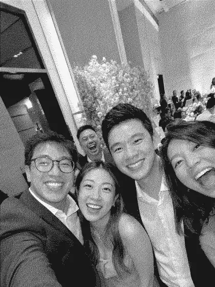Friends taking a selfie together at a wedding reception, shown in a grainy black-and-white print style.