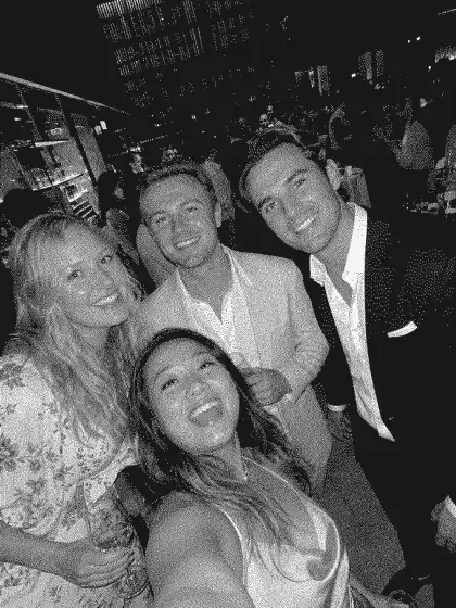 Four event guests taking a black-and-white group selfie at a reception