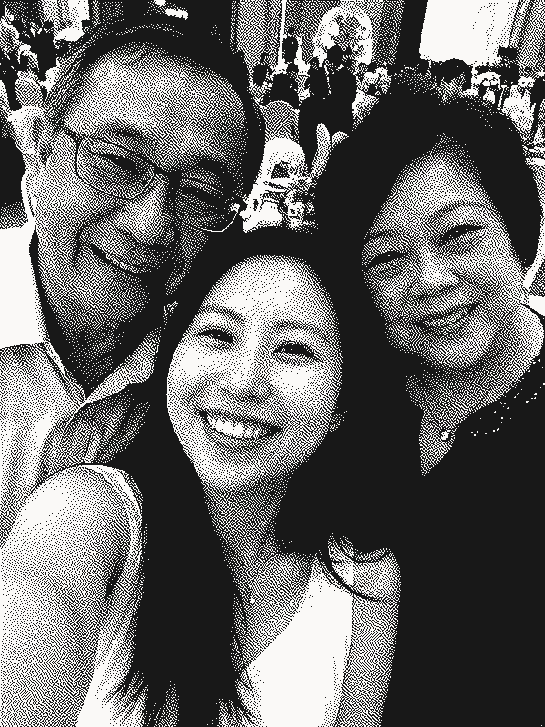A guest taking a smiling selfie with her parents at a wedding banquet, shown as a grainy black-and-white print.